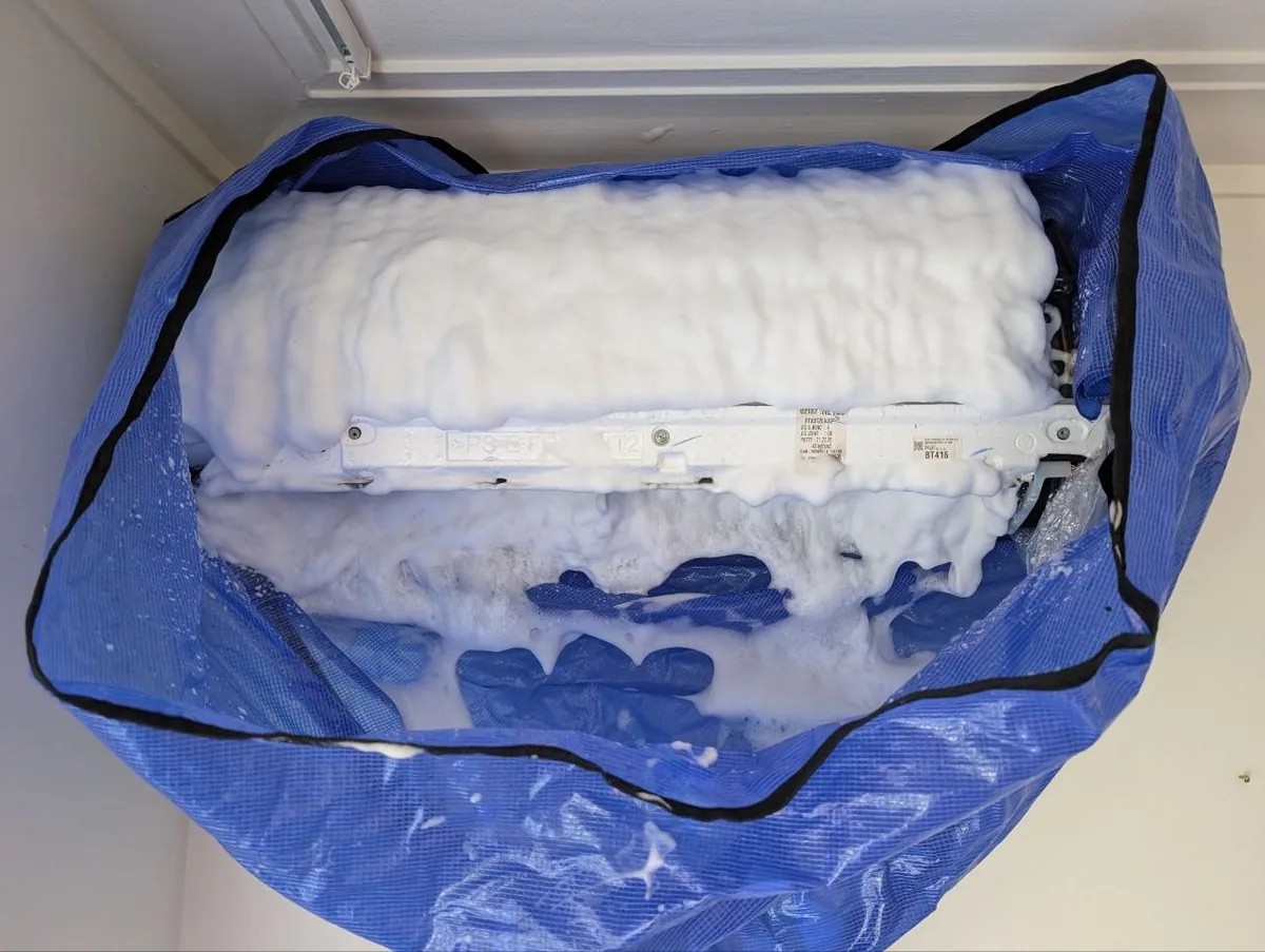 Wall-mounted mini-split protected by a blue cleaning bib during a Climeo service visit